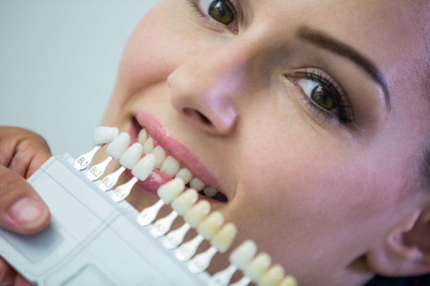 dentist-examining-female-patient-with-teeth-shades_107420-74180.jpg